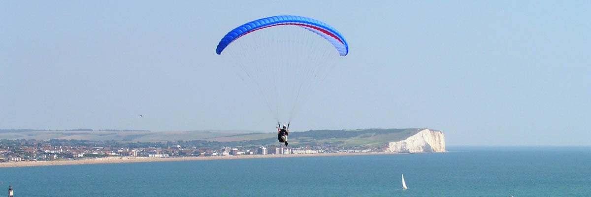 blue paraglider flying at Newhaven cliffs